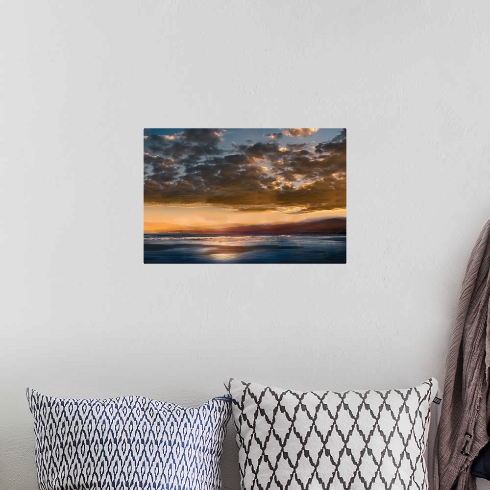 A bohemian room featuring Seascape photograph with mountains in the distance and a cloudy sky at sunset.