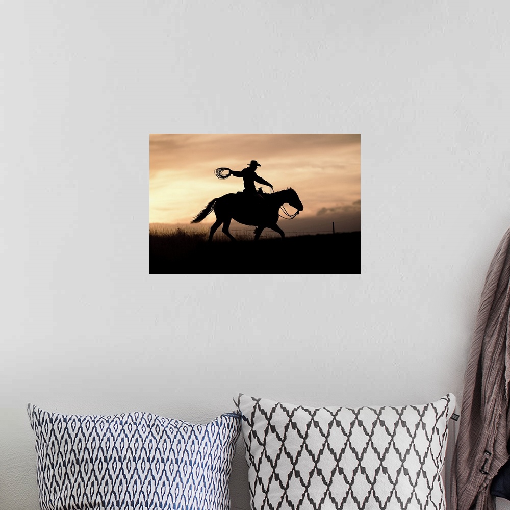 A bohemian room featuring A photograph of a silhouette of a cowboy riding a horse in a field with a sunset.