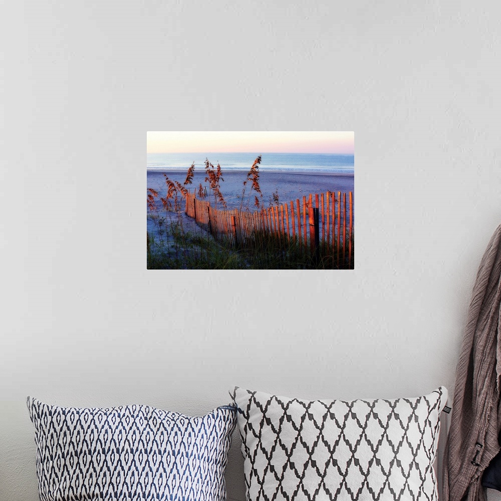 A bohemian room featuring Large photograph highlights a warm sunrise as it shines onto the fence and high grass in the fore...