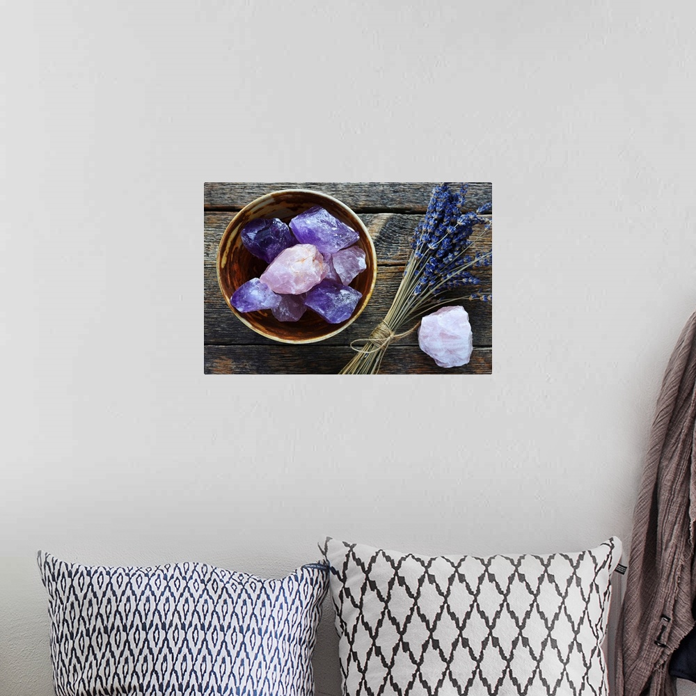 A bohemian room featuring A table top image of a pottery bowl with large rose quartz and amethyst crystal with dried lavend...