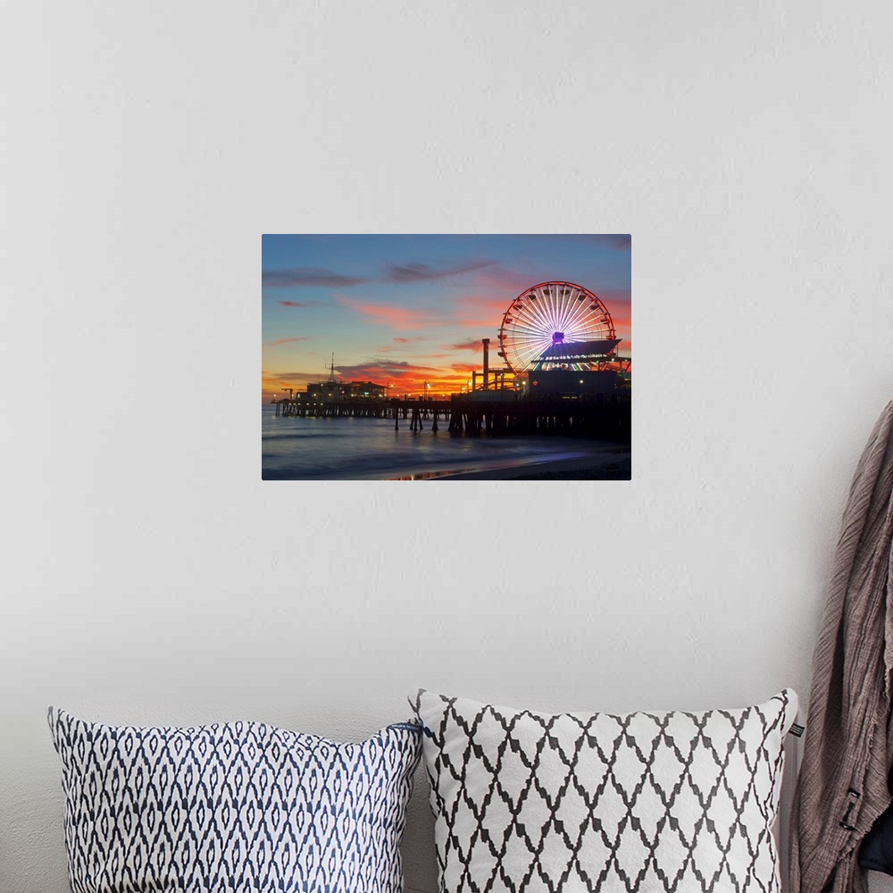 A bohemian room featuring Large artwork of a beach pier during sunset skies with the rides lit up and ocean waves calmly cr...