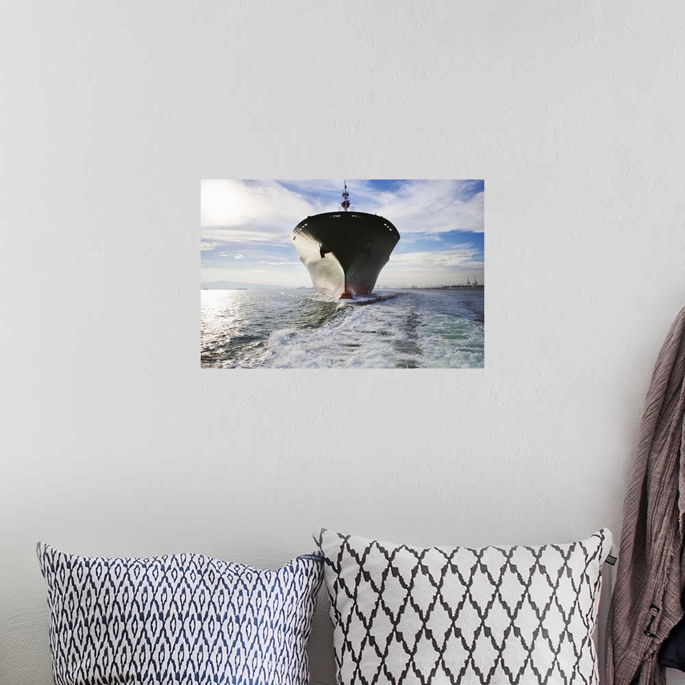 A bohemian room featuring Bow view of cargo ship sailing out of port.
