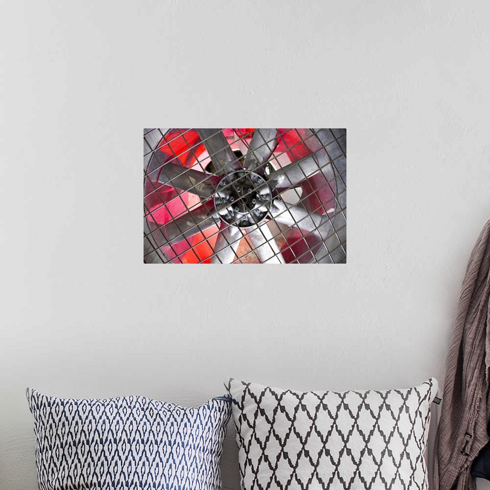 A bohemian room featuring Close-up of an industrial ventilation fan with red hues lighting up the back.