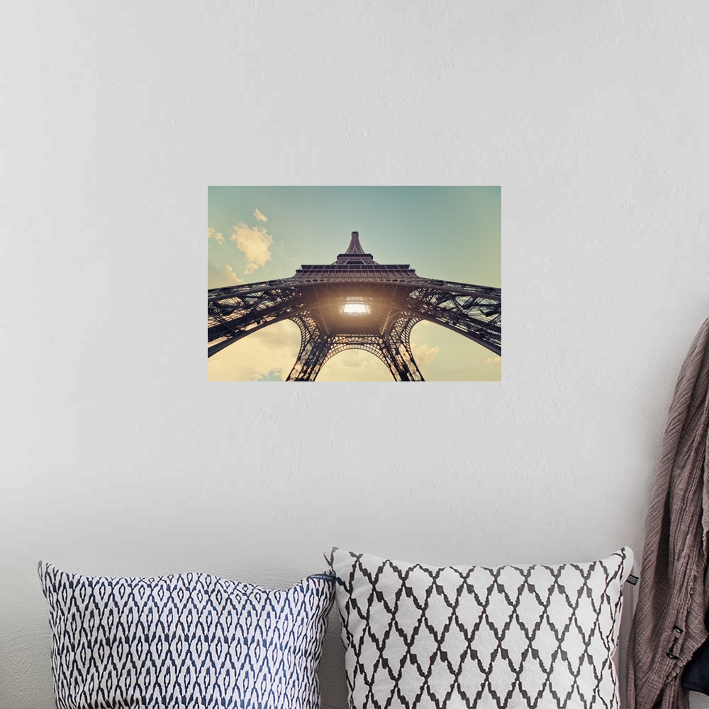 A bohemian room featuring Eiffel Tower with sun shining through center.