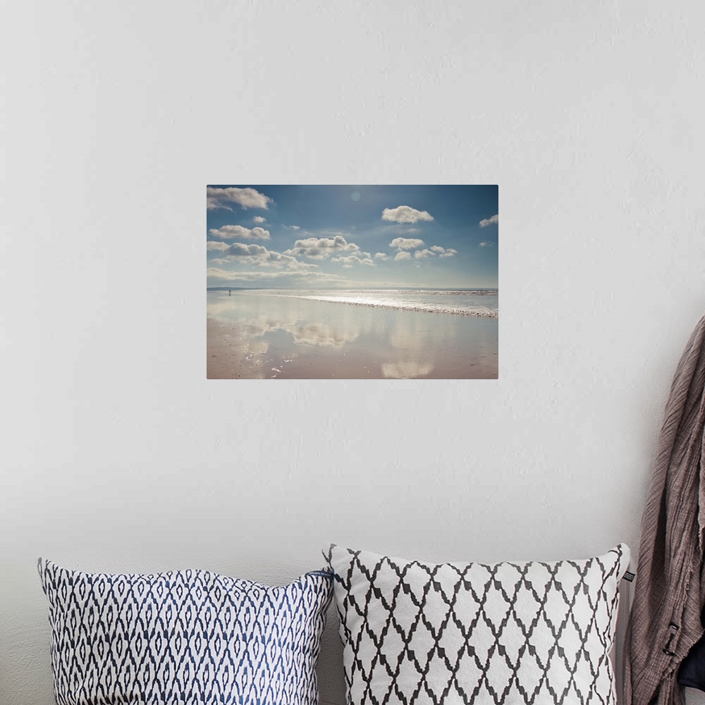 A bohemian room featuring Empty beach with a thin film of water reflecting fluffy clouds in a sunny blue sky.