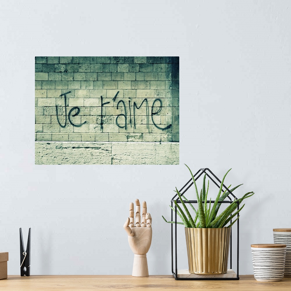 A bohemian room featuring Big canvas photo of a stone wall with the words "I love you" in French sprayed painted on it.