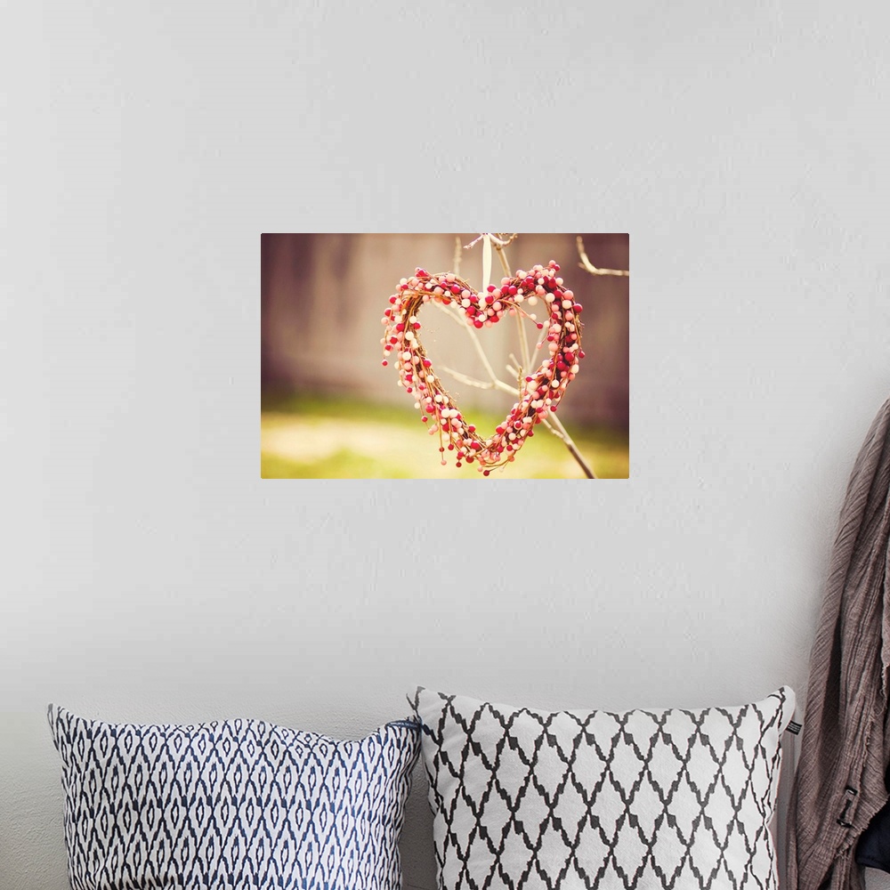 A bohemian room featuring Heart wreath made out of red, white and pink beads hanging on tree.