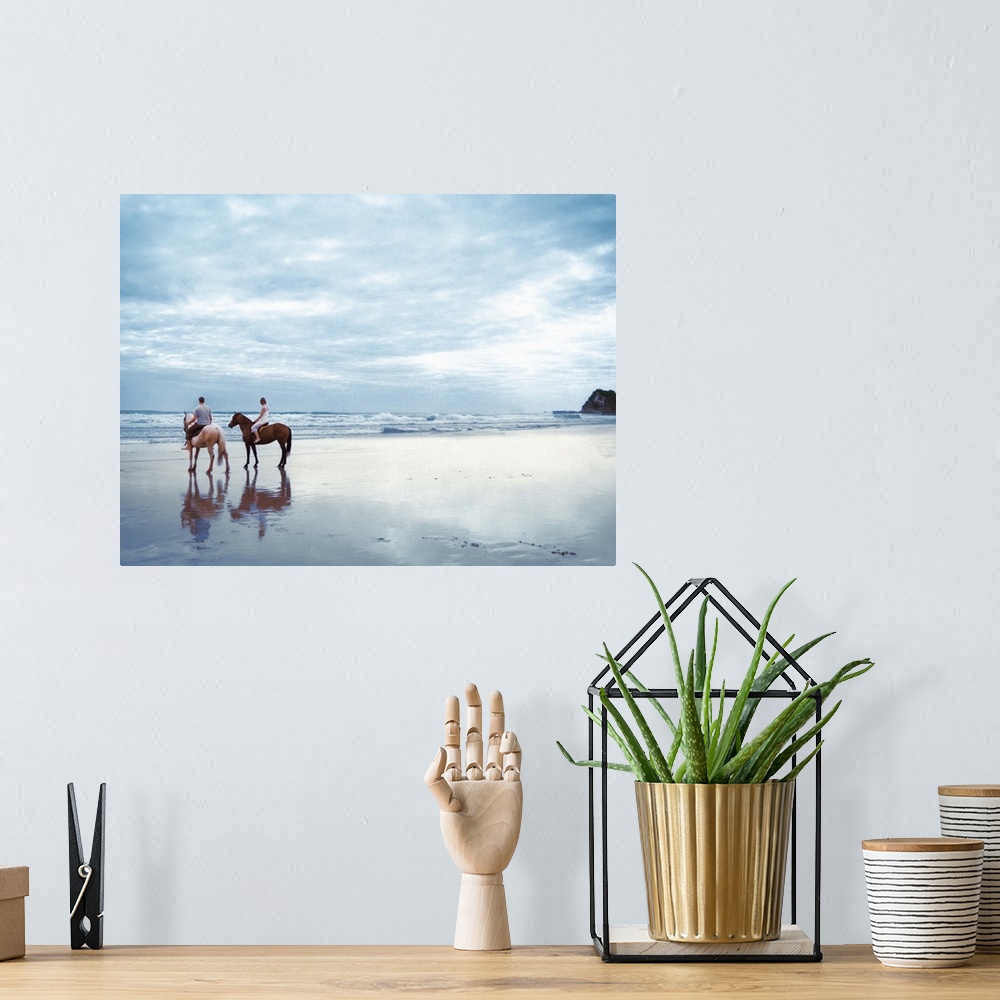 A bohemian room featuring A couple riding horses on Parkiri beach in New Zealand.