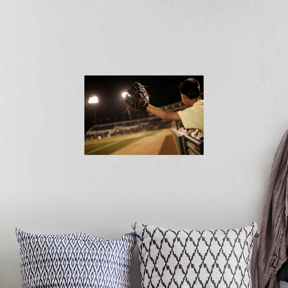 A bohemian room featuring Kid leaning over wall to try and catch 'foul 'ball  (hit out of play)at nighttime baseball game