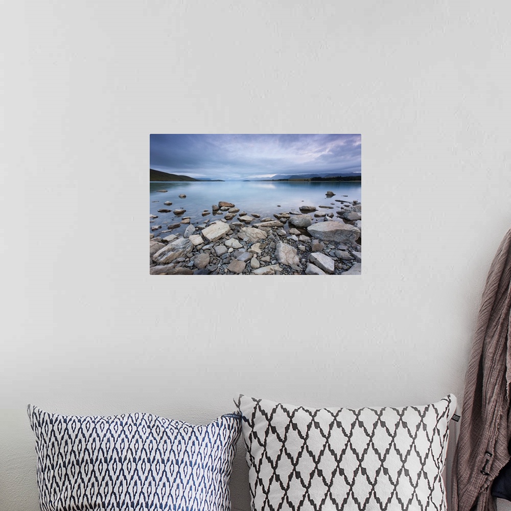 A bohemian room featuring Lake Tekapo in New Zealand, with rocks in foreground during morning cloud.