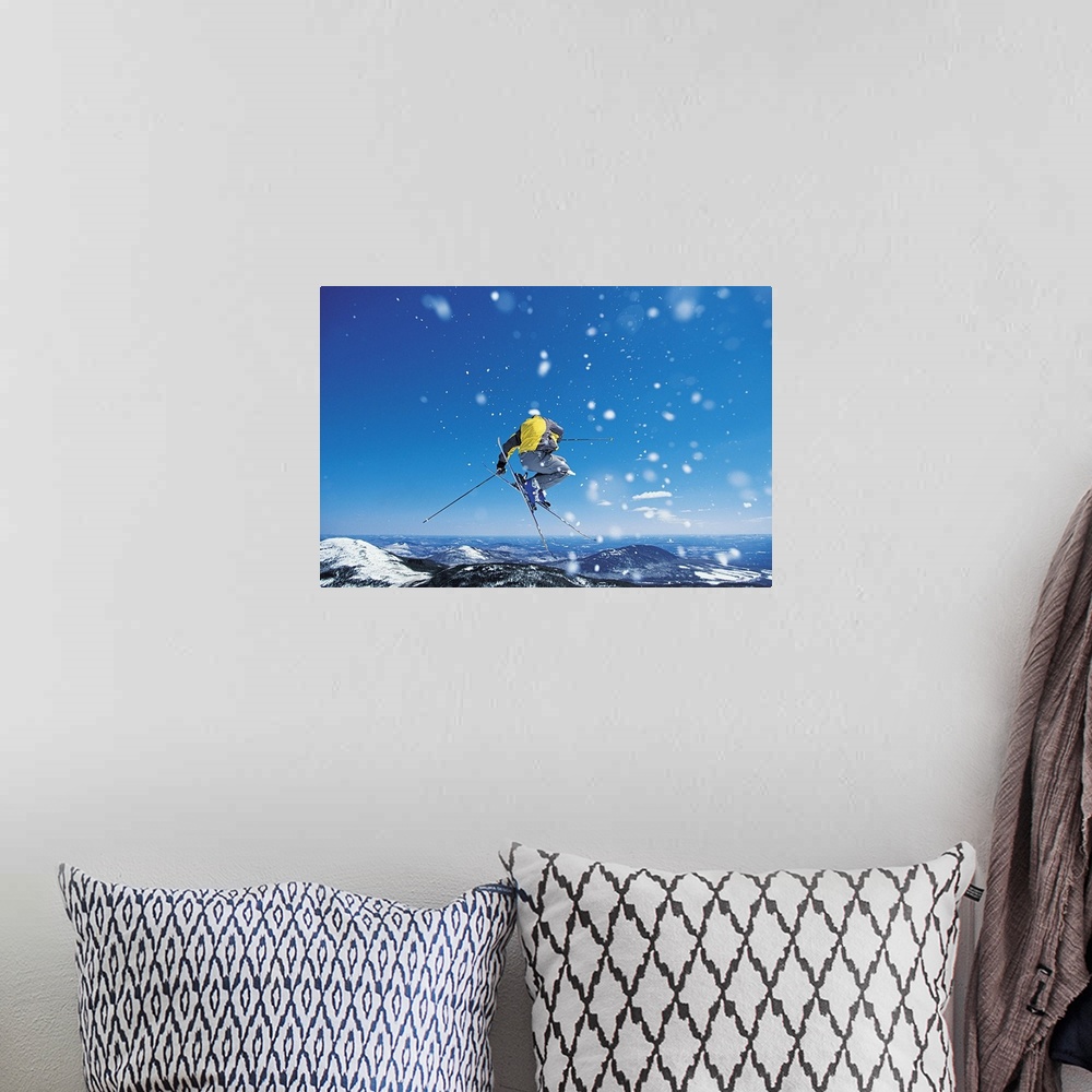 A bohemian room featuring Photograph of man on skis in mid air jump over snow covered mountains.