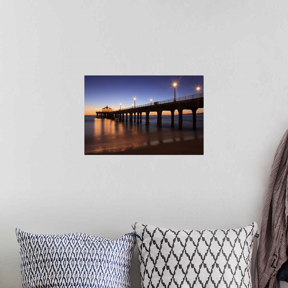 A bohemian room featuring Big canvas print of a pier that is silhouetted against a sunset with lights lit up along it.