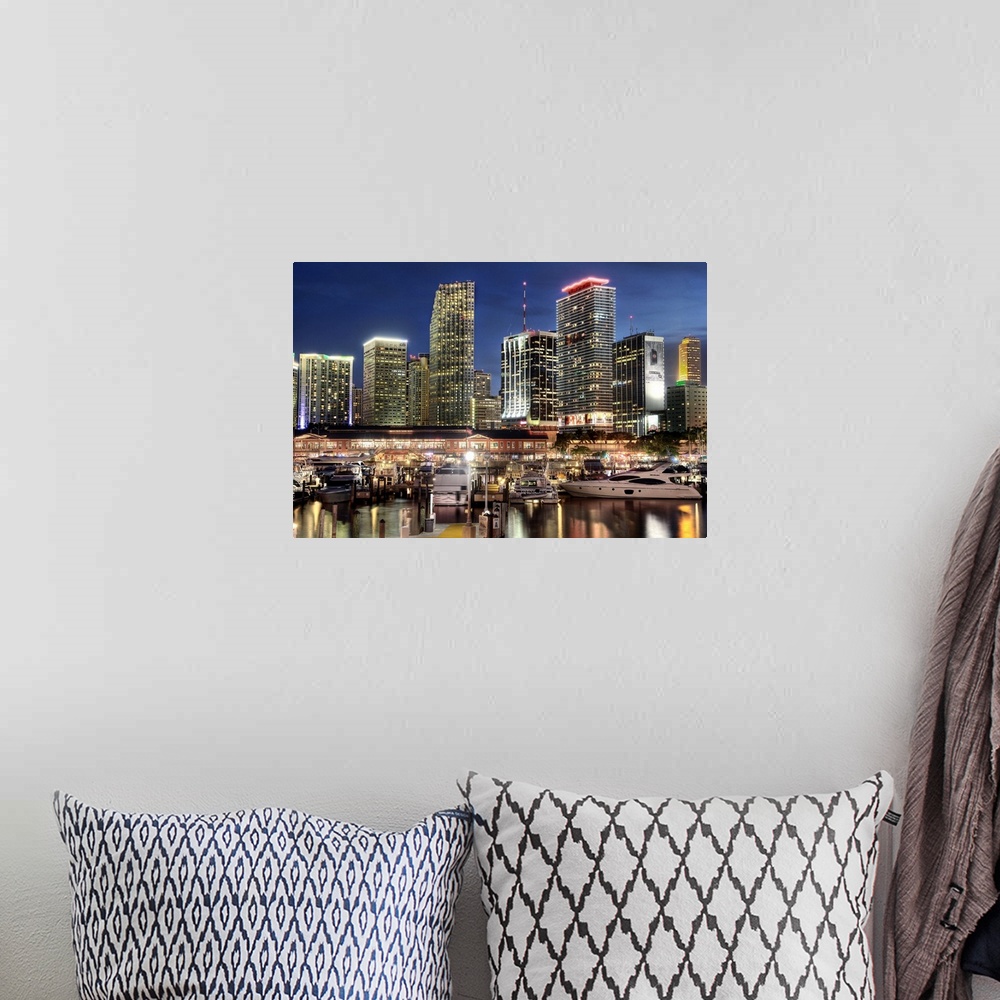 A bohemian room featuring Photograph of the nighttime lit up Miami skyline down at the harbor with boats parked in their wa...