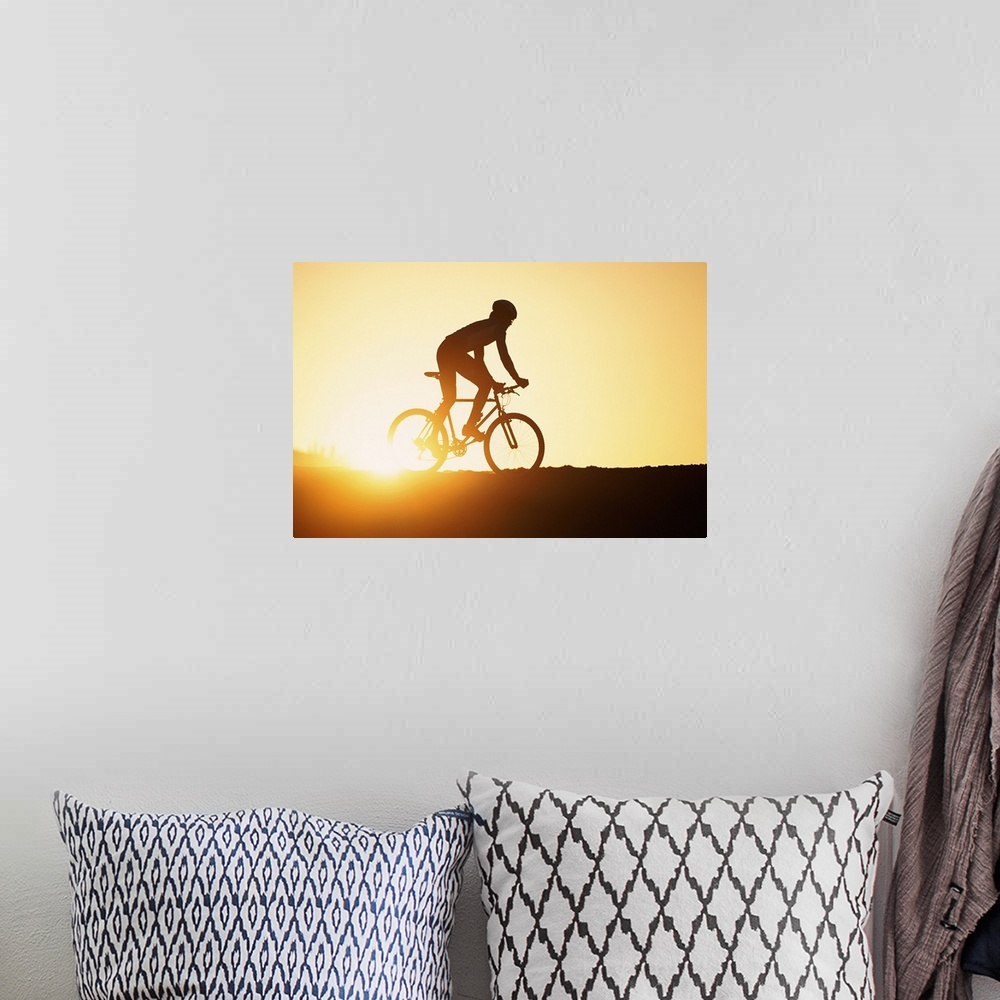 A bohemian room featuring Silhouette of man riding mountain bike at sunset