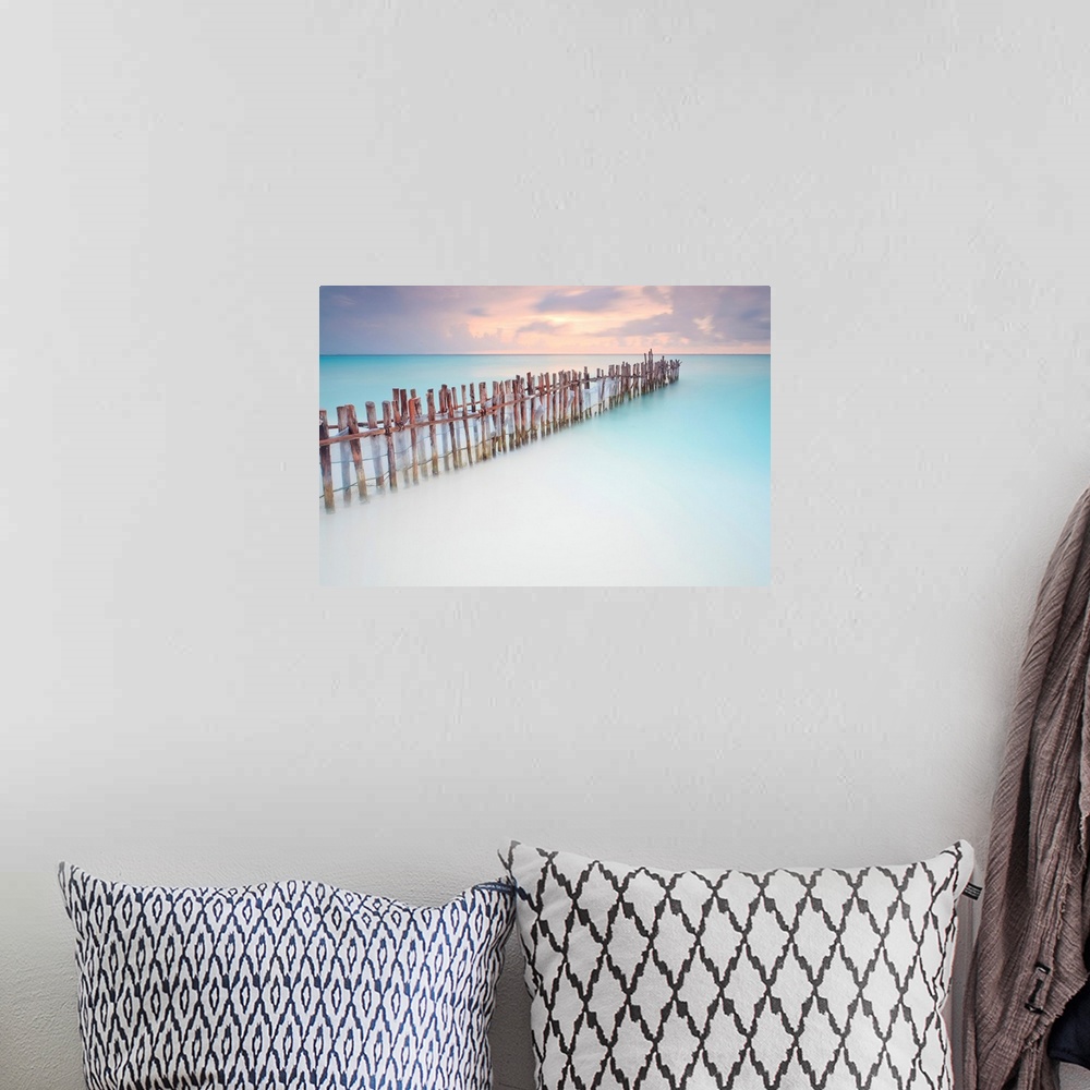 A bohemian room featuring Tranquil scene of Wooden posts in Caribbean sea, at sunset right after storm.