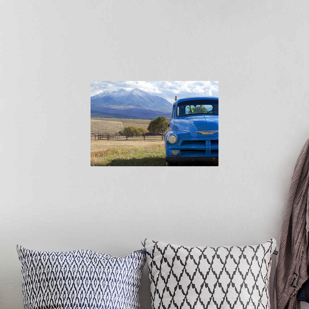 A bohemian room featuring Landscape, large photograph of part of the front of a blue, vintage truck, parked in a grassy fie...