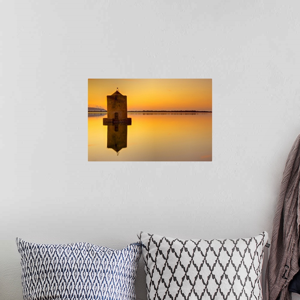 A bohemian room featuring Windmill at sunset in middle of water and reflection in water.