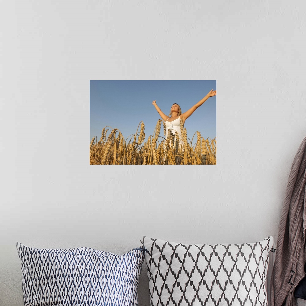 A bohemian room featuring Young woman in corn field with spread arms looking up.