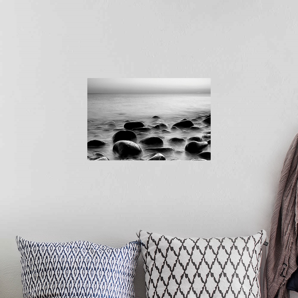A bohemian room featuring Black and white photograph of layers of smooth rocks covered by water.