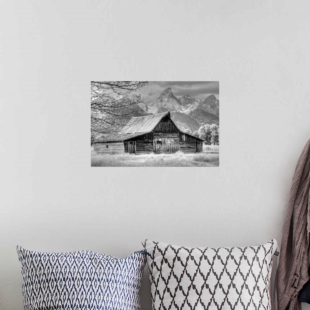 A bohemian room featuring Black and white photo of an old barn in a field with the Grand Teton mountain range in the distance.