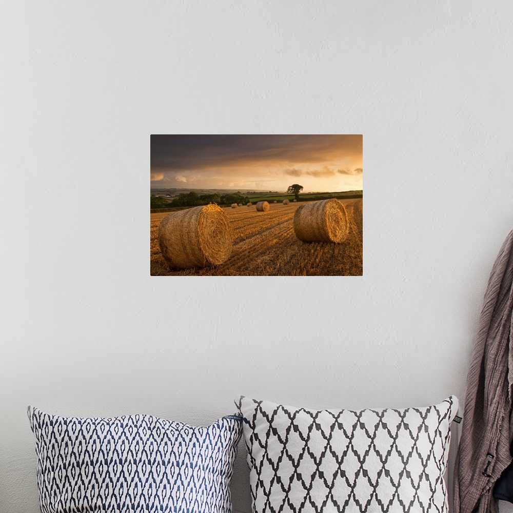 A bohemian room featuring Hay Bales in a ploughed field at sunset, Eastington, Devon, England. Summer (August)