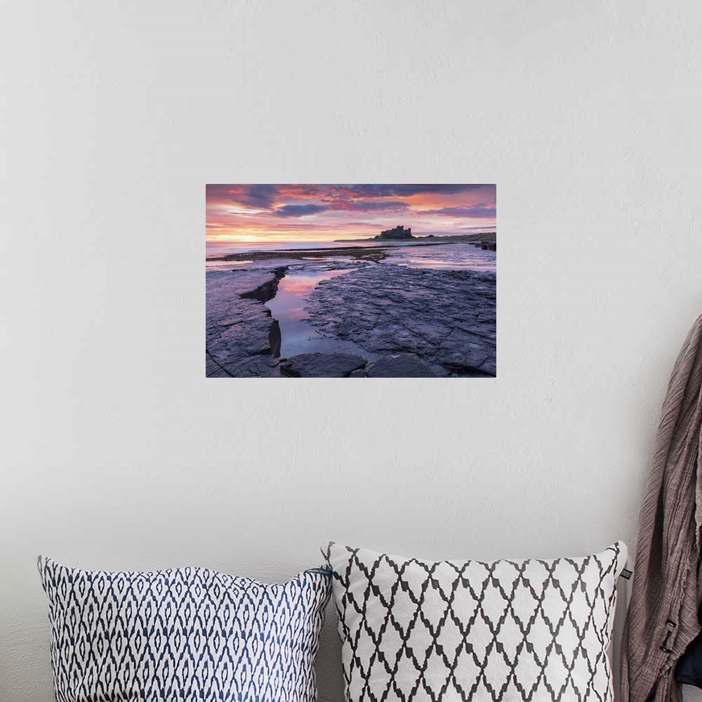 A bohemian room featuring Sunrise over Bamburgh Castle from the rocky shores of Bamburgh Beach, Northumberland, England. Au...
