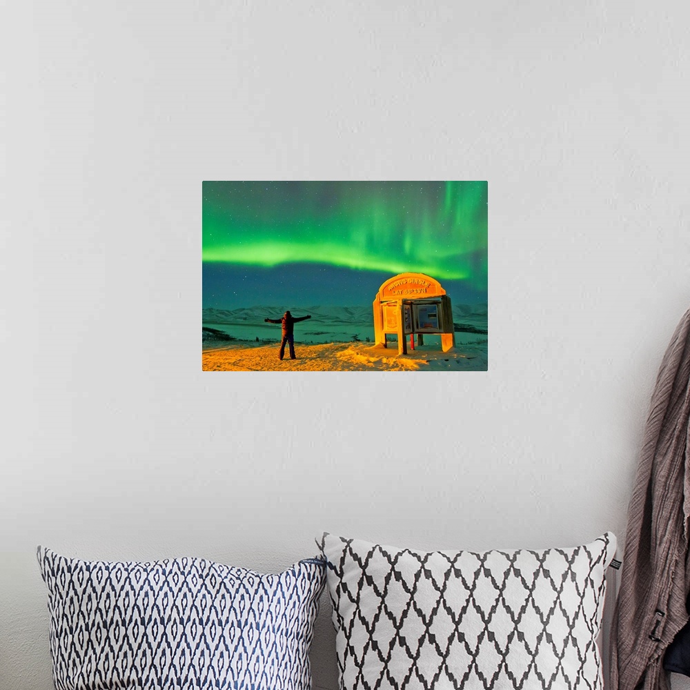 A bohemian room featuring A man looks in awe at the northern lights near the Arctic Circle sign.