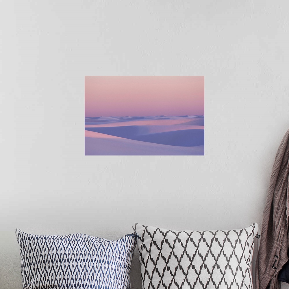 A bohemian room featuring Pink and purple illuminated sand dunes during sunset.