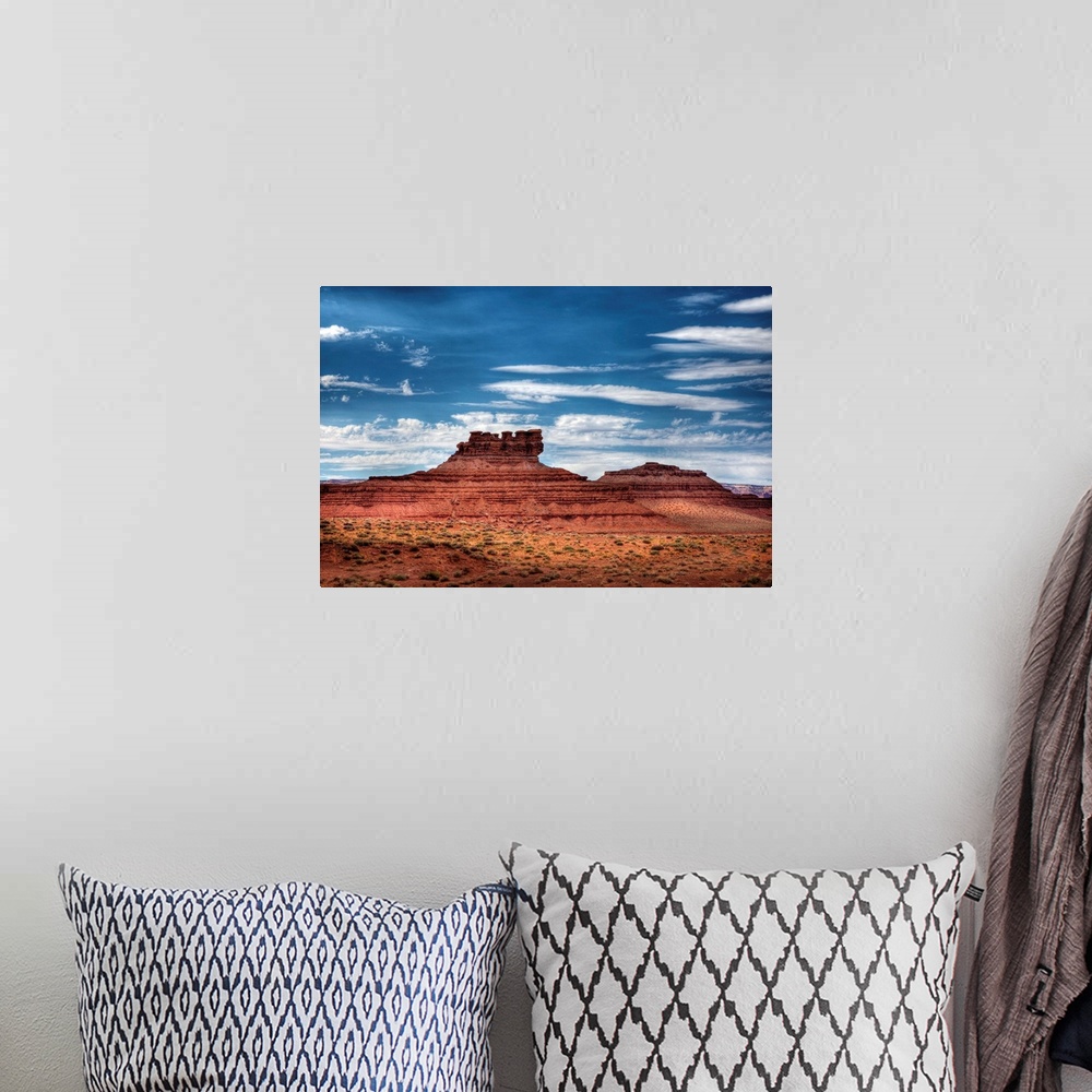 A bohemian room featuring A photograph of red desert landscape with an intricate rock formation in the distance.