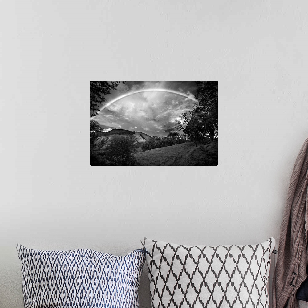 A bohemian room featuring Black and white photograph of a wilderness landscape with a large rainbow in the sky.