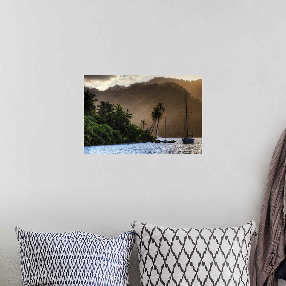 A bohemian room featuring A photograph of a tropical destination with a silhouetted sailboat in the distance.