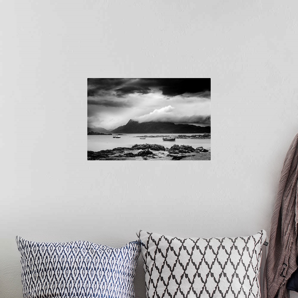 A bohemian room featuring Black and white landscape photograph of a cloudy sky over a mountainous lake with boats.