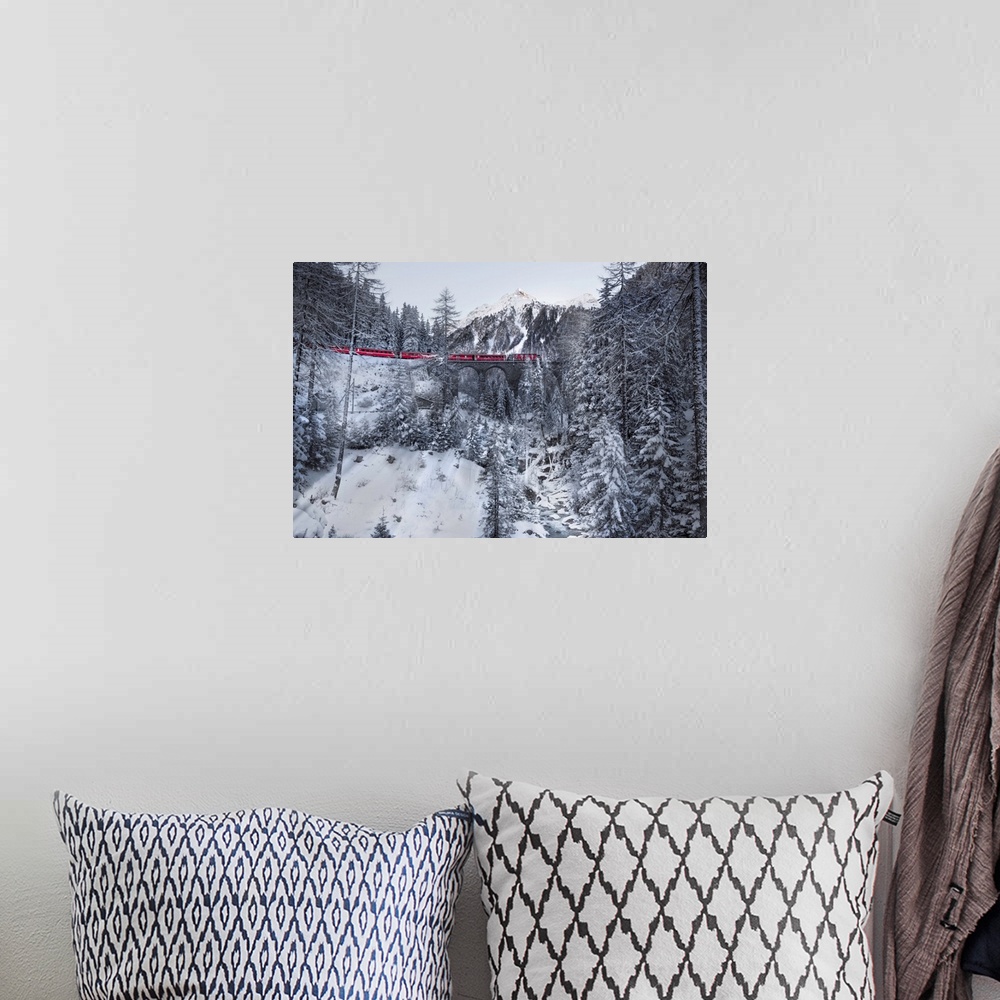 A bohemian room featuring Photograph of a red train passing through a snowy mountainous valley in winter along an arched ra...