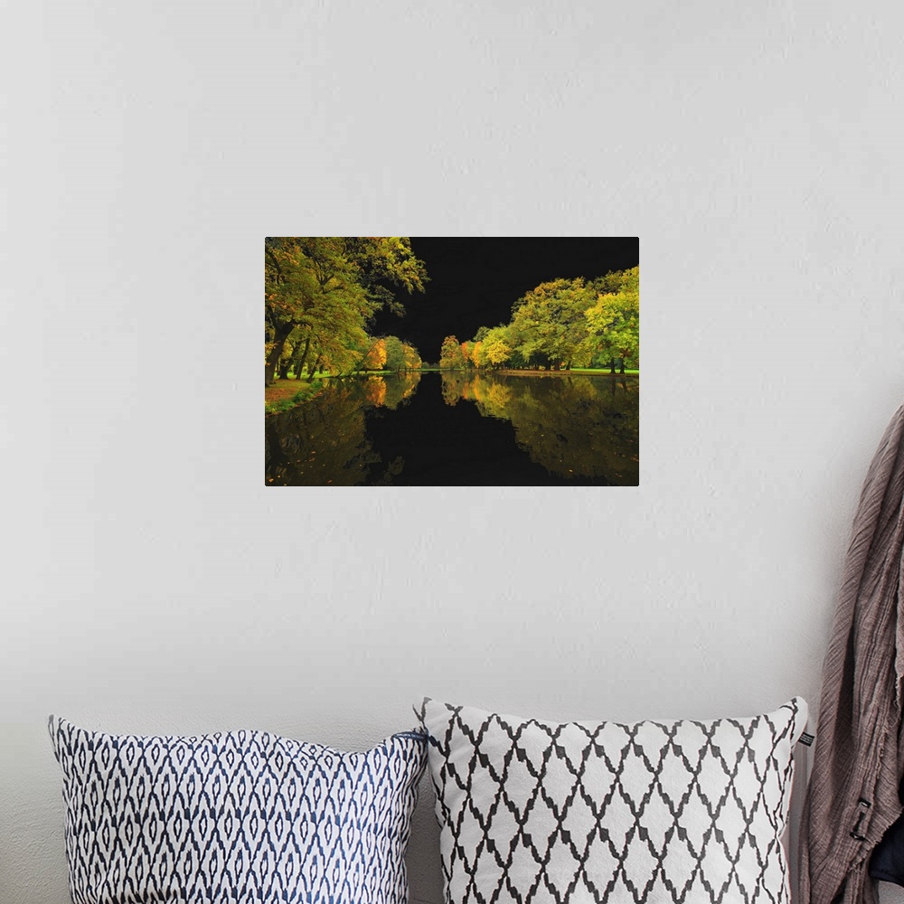 A bohemian room featuring Autumn trees lining a lake and reflecting into the water, with a dark black sky.