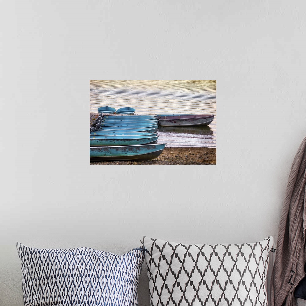 A bohemian room featuring A photograph of blue row boats sitting on the shoreline of a lake.