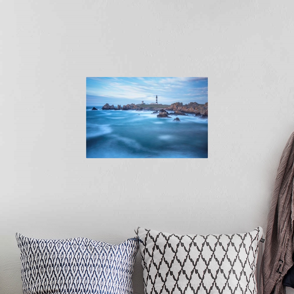 A bohemian room featuring Fine art photo of a lighthouse on a rocky coast with a cloudy sky and deep blue ocean.