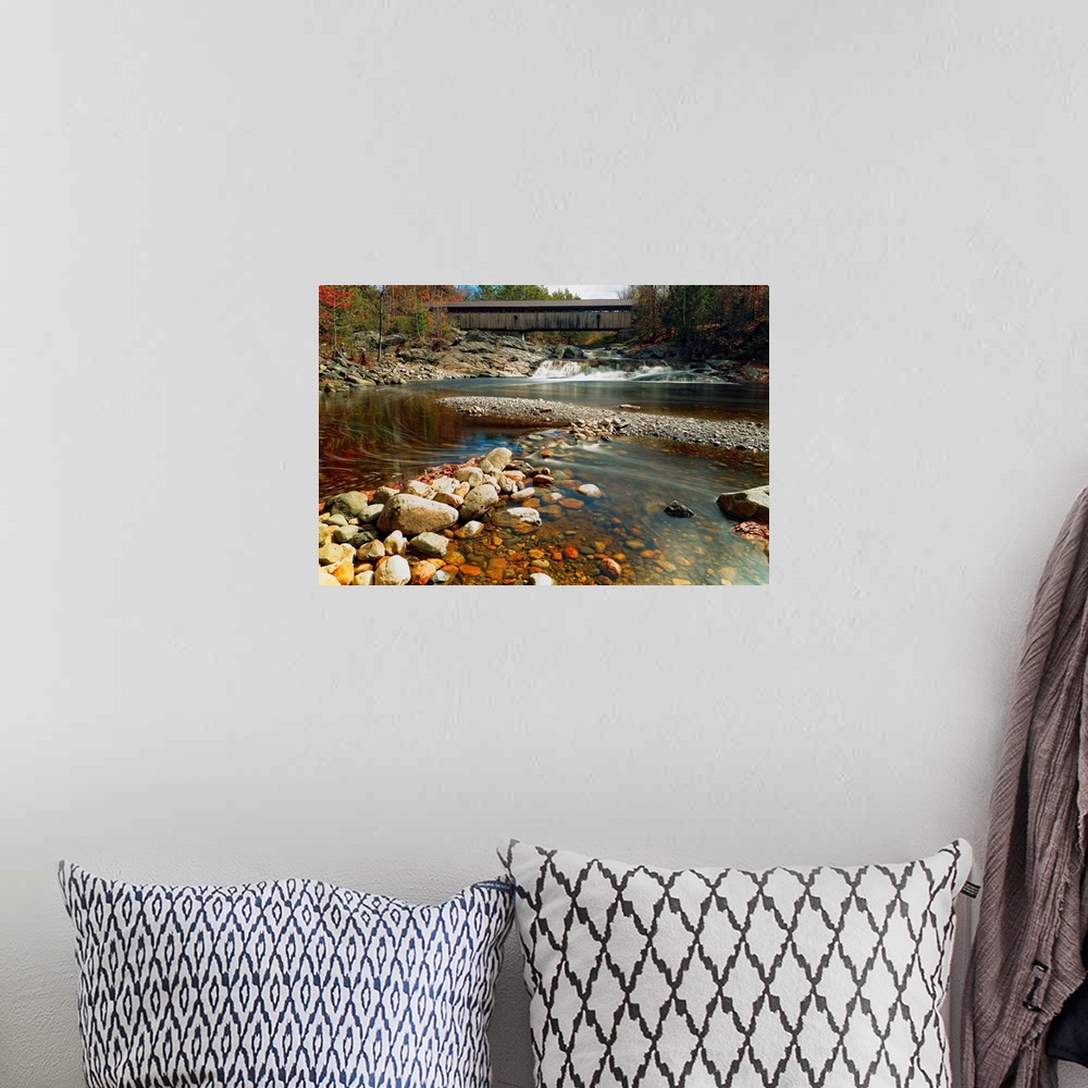 A bohemian room featuring A rocky riverbed in New Hampshire with the Swiftwater Covered Bridge in the distance.