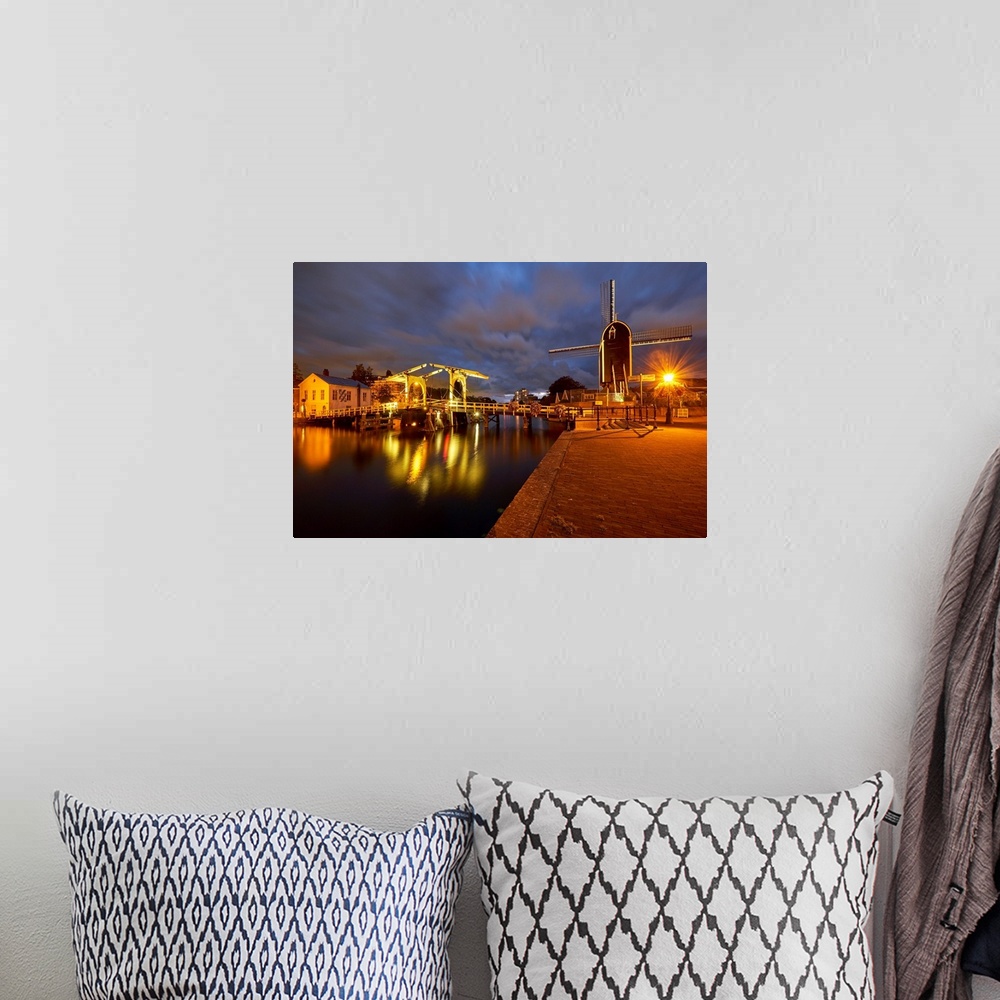 A bohemian room featuring View of a canal with a small bridge and windmill at night, Leiden, South Holland, Netherlands.