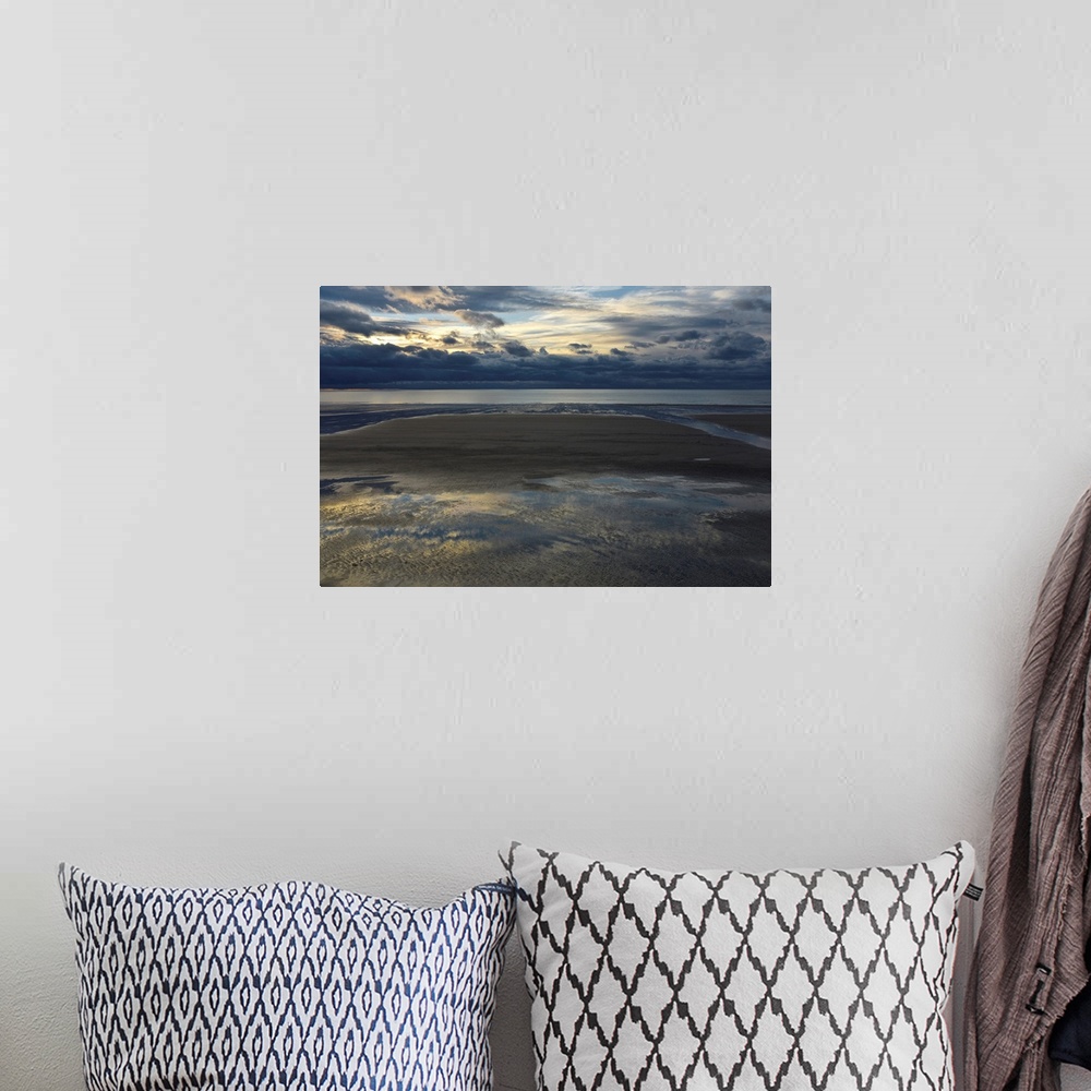 A bohemian room featuring Landscape photograph of an empty beach on a cloudy day with the sky reflecting onto the puddles i...