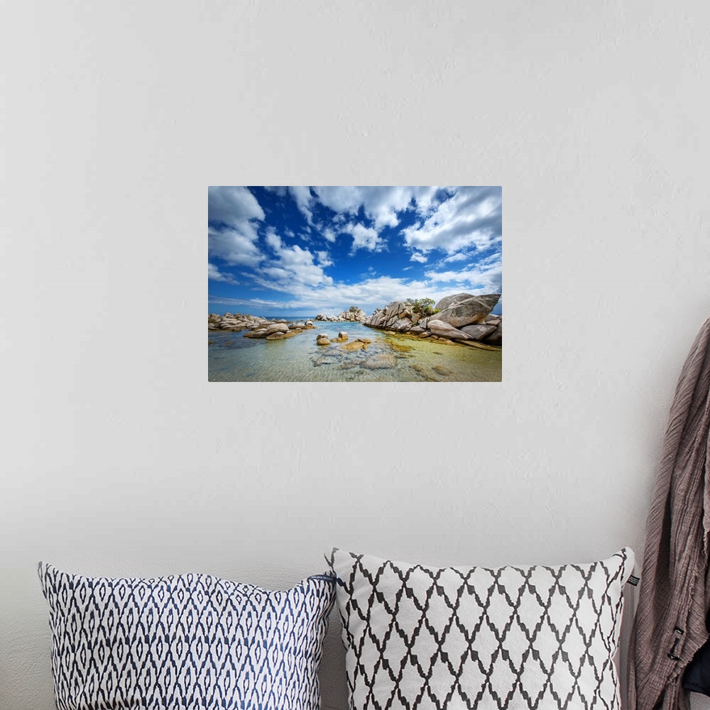 A bohemian room featuring A photograph of a rocky coastline under a sky filled with dramatic clouds.