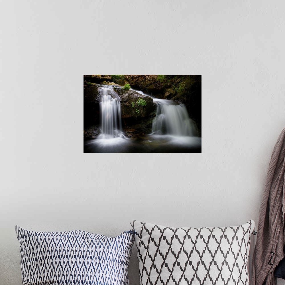 A bohemian room featuring A photograph of a waterfall streaming down rocks in a forest.