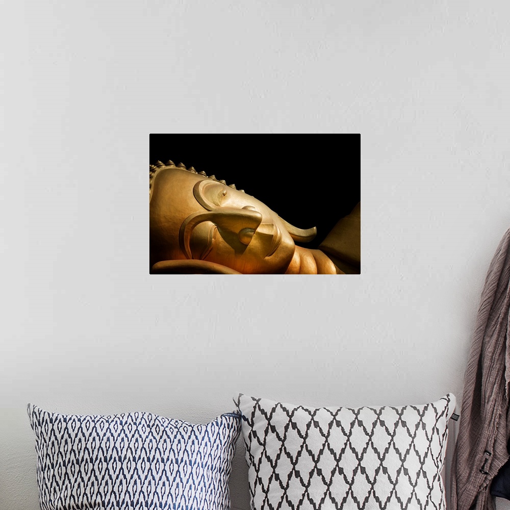 A bohemian room featuring The head of a reclining Buddha in front of a black background