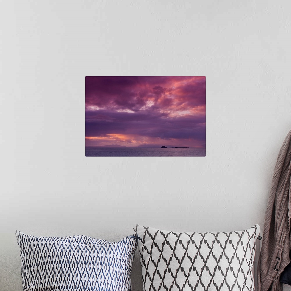 A bohemian room featuring Fine art photo of a dramatic skyscape over a calm ocean with a small island in the distance.