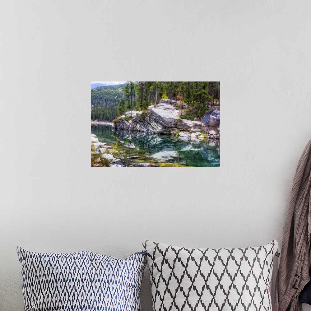 A bohemian room featuring Reflections of the forest and rocks in calm water.