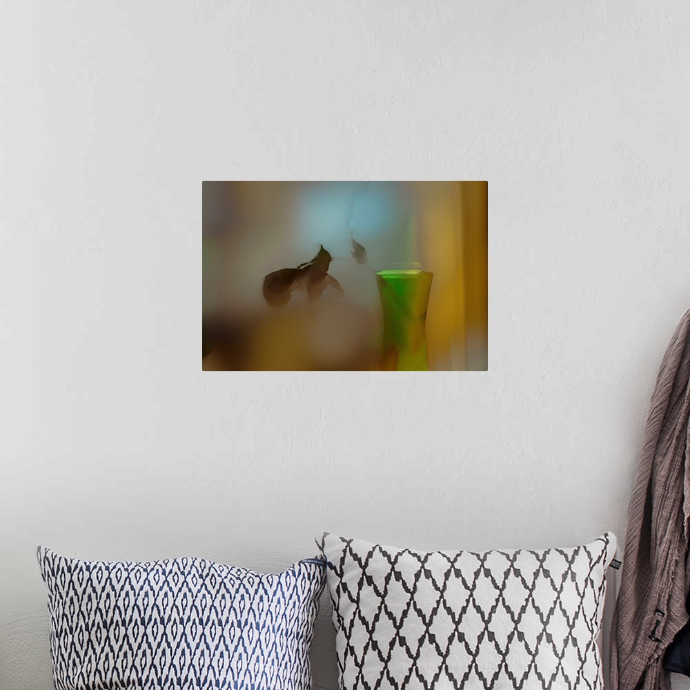 A bohemian room featuring A soft of focus photo of a dying plant inside a vase.