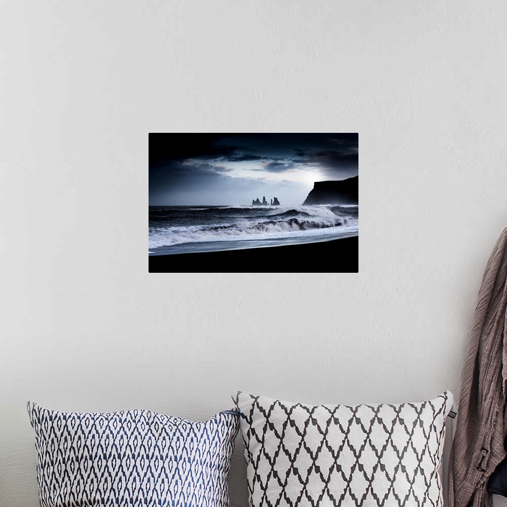 A bohemian room featuring A photograph of a dark rugged coastline under a dark sky.