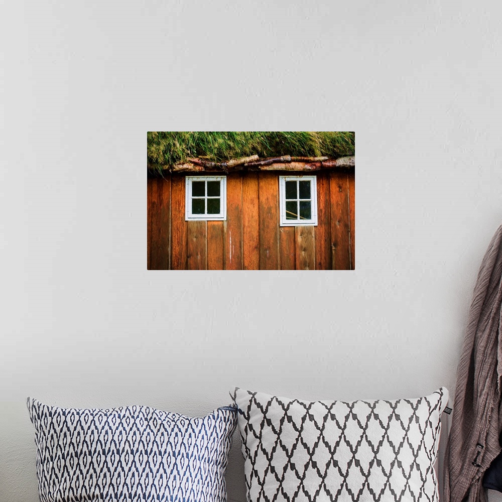 A bohemian room featuring Two little windows in a wooden wall with a grassy roof.