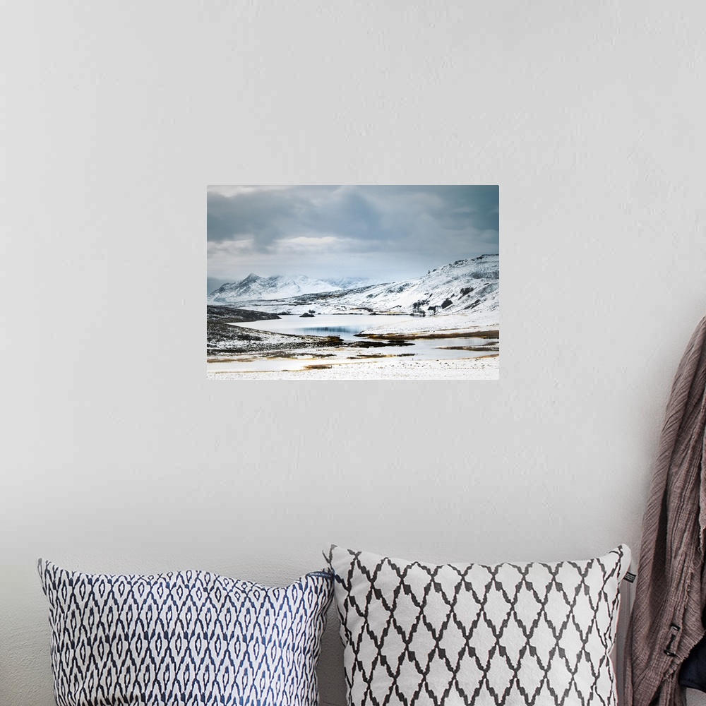 A bohemian room featuring Scottish Mountains in the snow with a small cottage beside a lake.