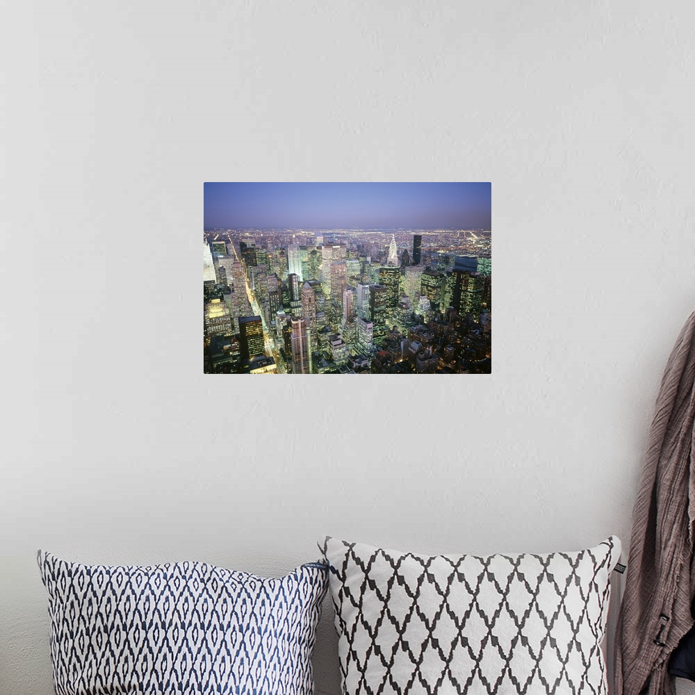 A bohemian room featuring A photograph taken from the top of a building of the endless city scape illuminated at night.