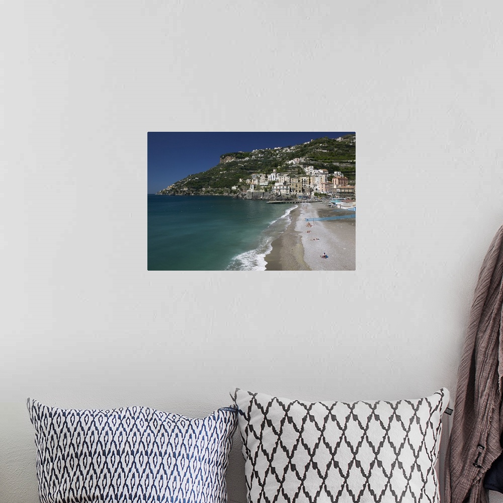 A bohemian room featuring A large cliff with buildings and homes built in it is photographed with the ocean water and beach...
